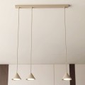 Beżowa lampa wisząca na listwie nad stół.
